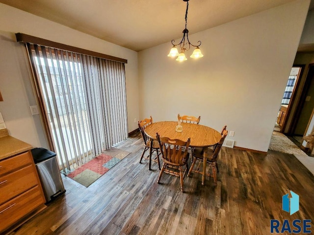 dining space with dark wood-type flooring and a chandelier