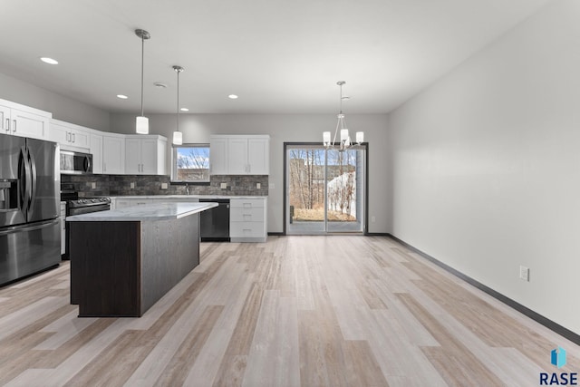 kitchen with pendant lighting, white cabinets, a center island, stainless steel appliances, and tasteful backsplash