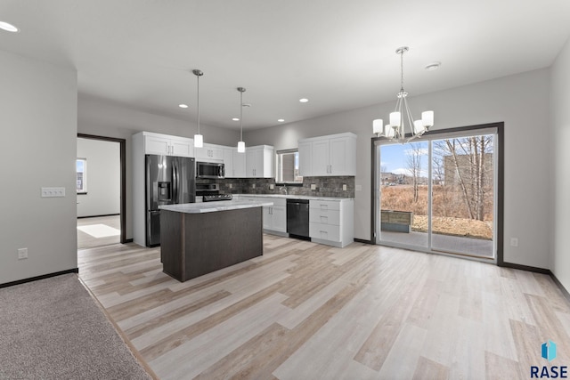 kitchen with appliances with stainless steel finishes, pendant lighting, white cabinetry, and a kitchen island