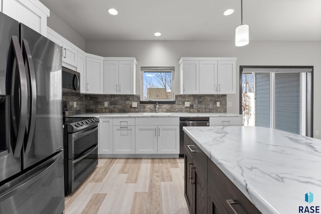 kitchen with pendant lighting, sink, white cabinetry, and black appliances