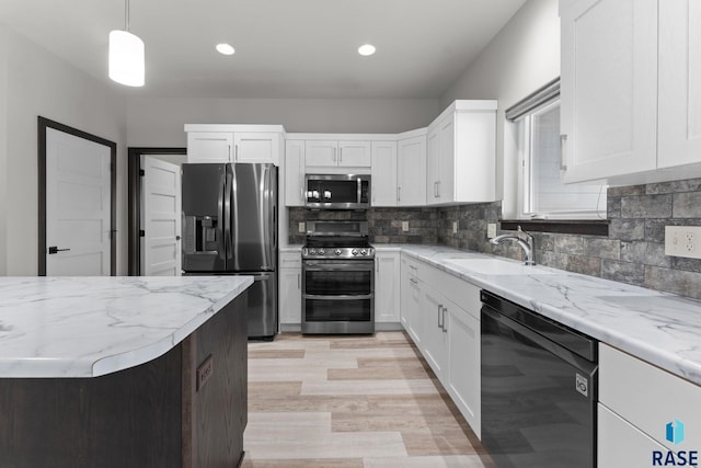 kitchen featuring white cabinets, stainless steel appliances, sink, backsplash, and hanging light fixtures