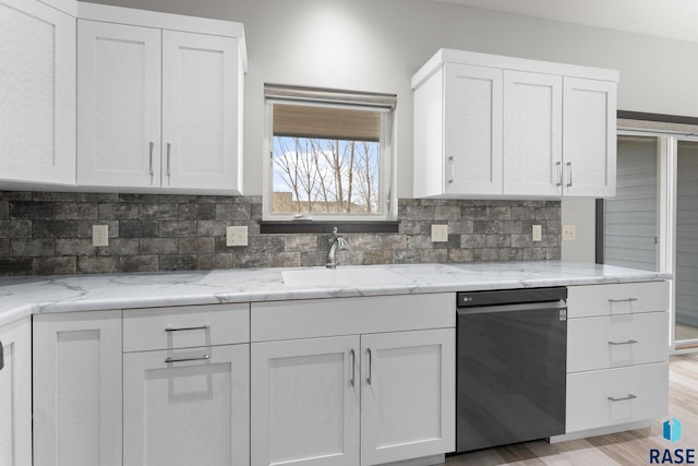 kitchen with tasteful backsplash, white cabinets, sink, and light stone counters