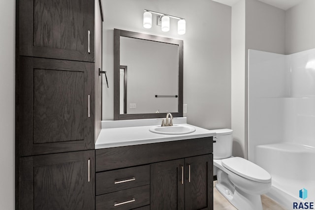 bathroom featuring a shower, toilet, and vanity