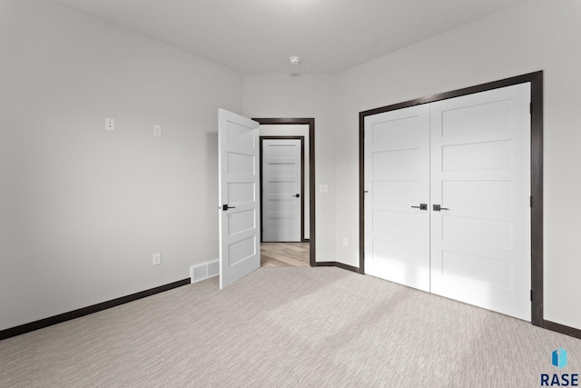 unfurnished bedroom featuring light colored carpet and a closet