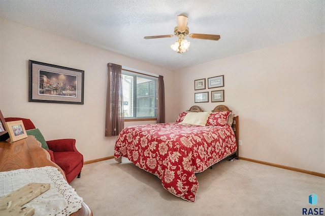 bedroom featuring a textured ceiling, ceiling fan, and light carpet