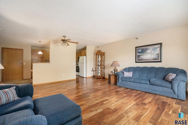 living room with a textured ceiling, ceiling fan, and hardwood / wood-style flooring