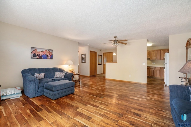 living room featuring ceiling fan, wood-type flooring, and a textured ceiling