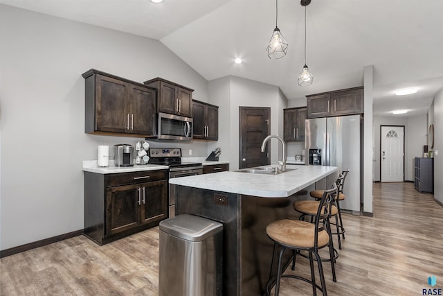 kitchen featuring sink, dark brown cabinetry, hanging light fixtures, a kitchen island with sink, and appliances with stainless steel finishes