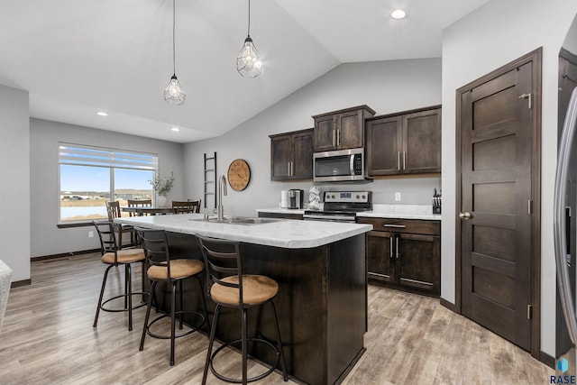 kitchen featuring pendant lighting, appliances with stainless steel finishes, an island with sink, sink, and a water view