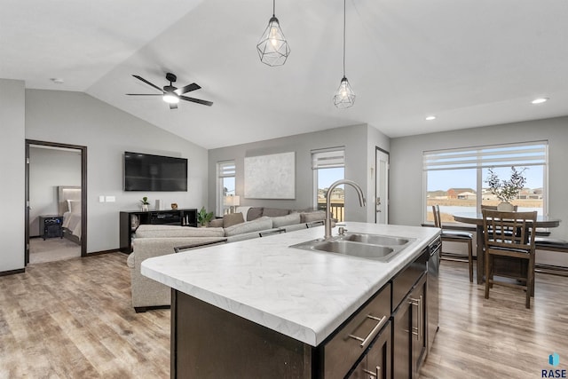 kitchen featuring light hardwood / wood-style floors, sink, hanging light fixtures, and an island with sink