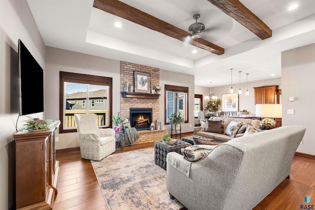 living room featuring a brick fireplace, wood-type flooring, a wealth of natural light, and ceiling fan