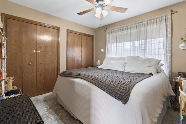 carpeted bedroom featuring ceiling fan and multiple closets