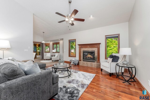 living room with ceiling fan, hardwood / wood-style floors, lofted ceiling, and a tiled fireplace