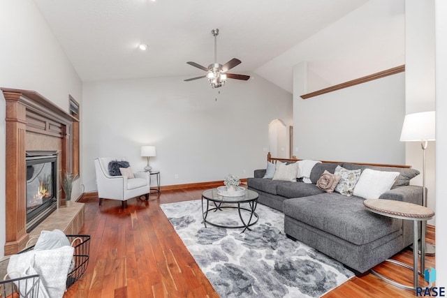 living room featuring a tile fireplace, vaulted ceiling, ceiling fan, and dark hardwood / wood-style flooring