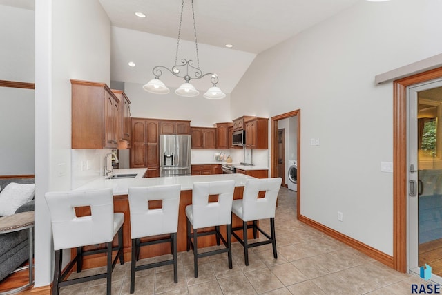 kitchen featuring washer / clothes dryer, sink, high vaulted ceiling, kitchen peninsula, and stainless steel appliances