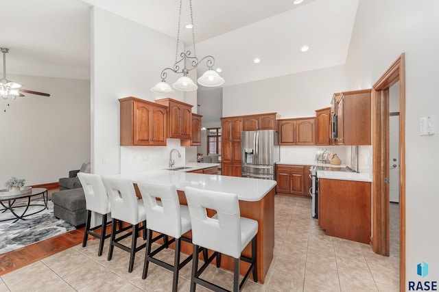 kitchen featuring a kitchen breakfast bar, appliances with stainless steel finishes, sink, light tile patterned floors, and high vaulted ceiling