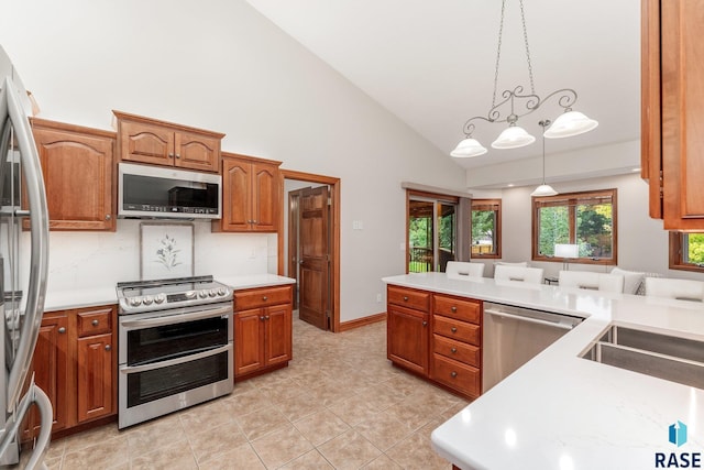 kitchen with decorative light fixtures, light tile patterned floors, high vaulted ceiling, and stainless steel appliances