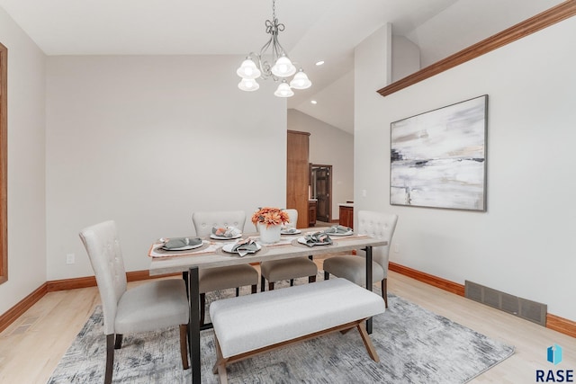 dining room with high vaulted ceiling, an inviting chandelier, and light wood-type flooring