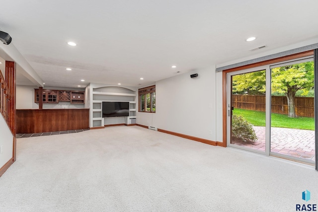 unfurnished living room featuring light carpet and built in shelves