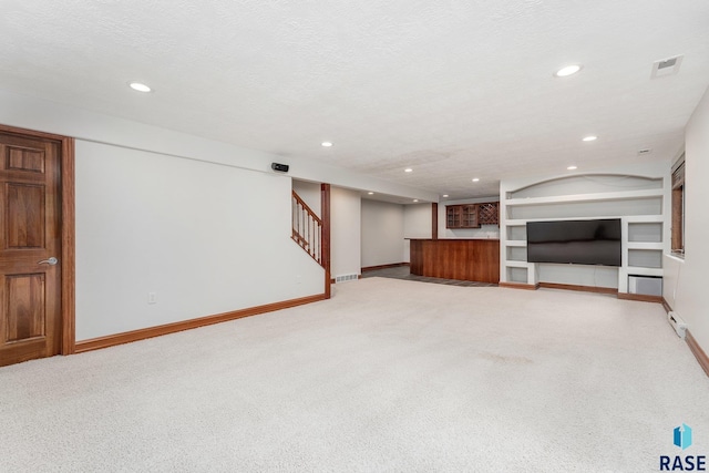 basement with a textured ceiling, built in features, and carpet flooring