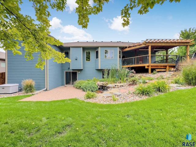 rear view of property featuring a patio area, a lawn, and a wooden deck