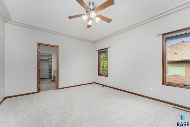 carpeted empty room featuring ceiling fan and crown molding