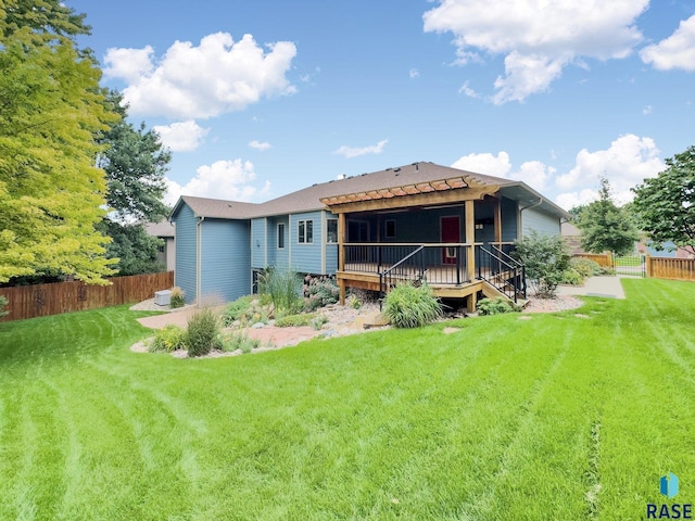 back of property with a wooden deck and a yard