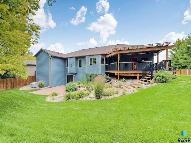 rear view of house with a lawn, a deck, and a patio