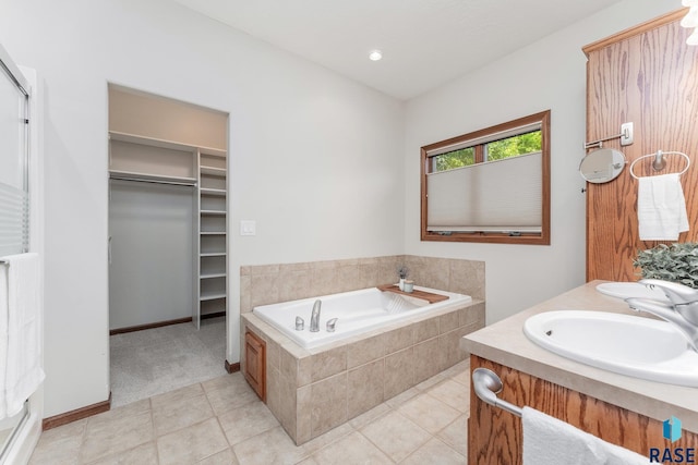 bathroom featuring a relaxing tiled tub, tile patterned floors, and vanity