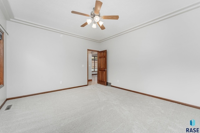 empty room featuring crown molding, light colored carpet, and ceiling fan