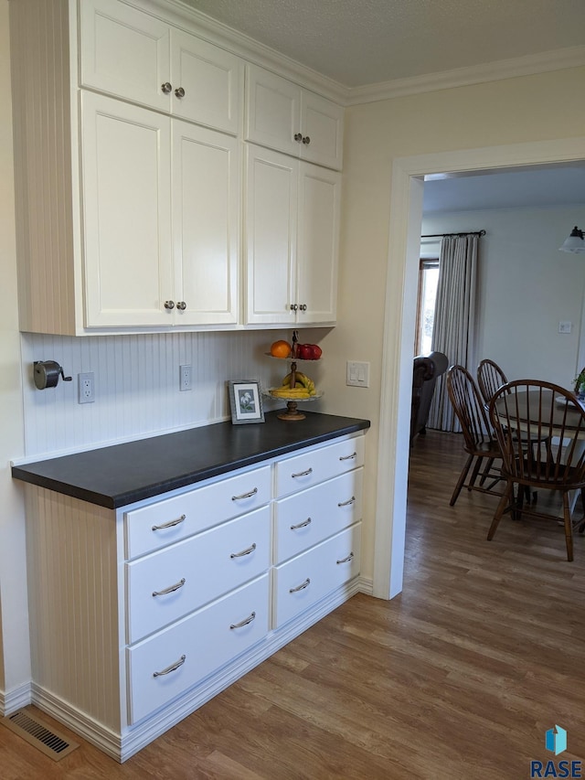 kitchen with ornamental molding, wood-type flooring, and white cabinets