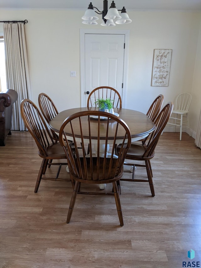 dining area with ornamental molding, a chandelier, and light hardwood / wood-style flooring