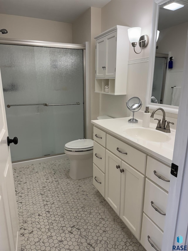 bathroom featuring toilet, tile patterned floors, a shower with shower door, and vanity