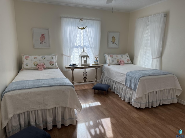 bedroom with a textured ceiling, crown molding, and hardwood / wood-style flooring