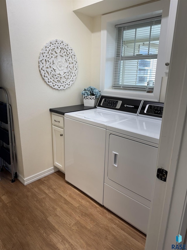 clothes washing area featuring light hardwood / wood-style floors, separate washer and dryer, and cabinets