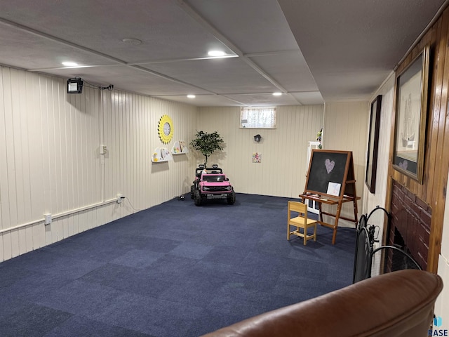 living area with carpet and wooden walls