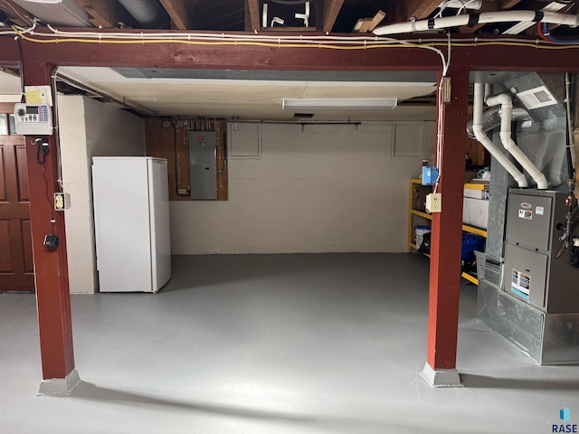 basement featuring electric panel and white refrigerator