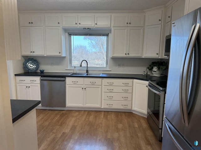 kitchen with white cabinets, light wood-type flooring, appliances with stainless steel finishes, and sink