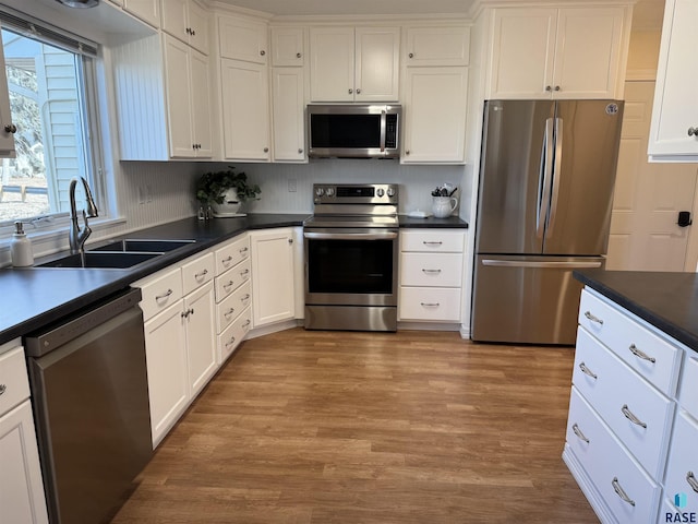 kitchen featuring white cabinets, appliances with stainless steel finishes, light hardwood / wood-style flooring, and sink