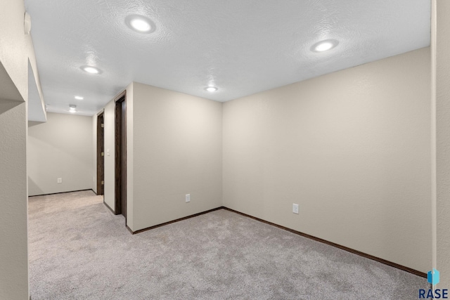 spare room with a textured ceiling and light colored carpet