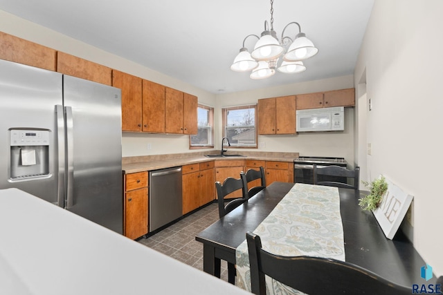 kitchen featuring sink, hanging light fixtures, appliances with stainless steel finishes, and a chandelier