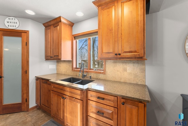 kitchen featuring sink, light stone counters, and decorative backsplash