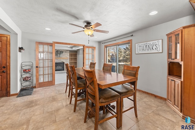 dining area featuring ceiling fan, a fireplace, and a textured ceiling