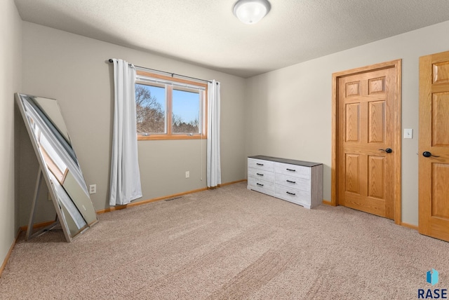 unfurnished bedroom featuring a textured ceiling and light carpet