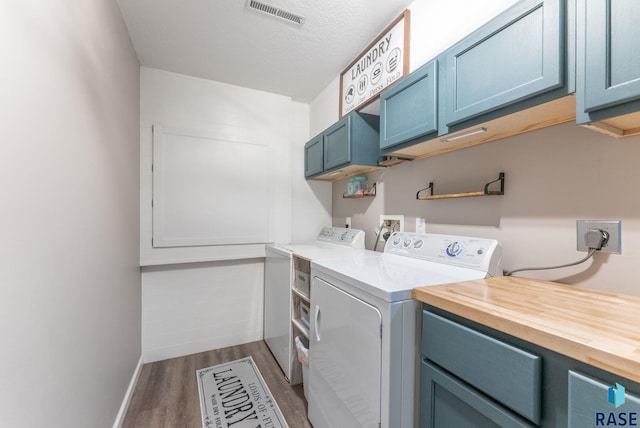 laundry room featuring dark hardwood / wood-style flooring, a textured ceiling, cabinets, and independent washer and dryer