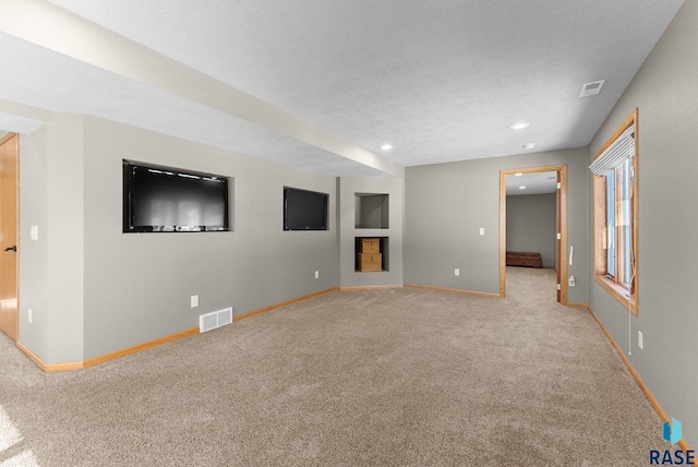 unfurnished living room featuring light colored carpet and a textured ceiling