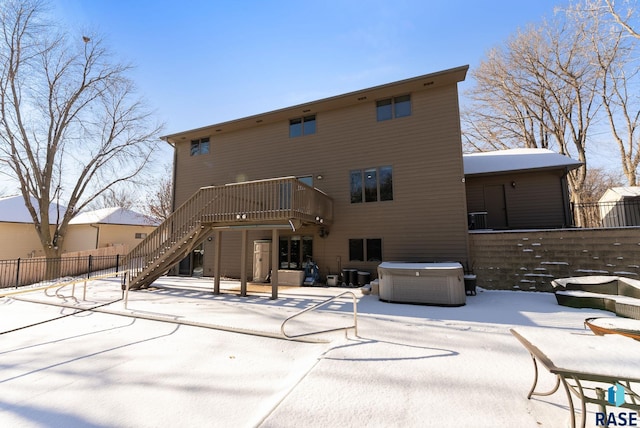 snow covered house with a deck, a hot tub, and central air condition unit