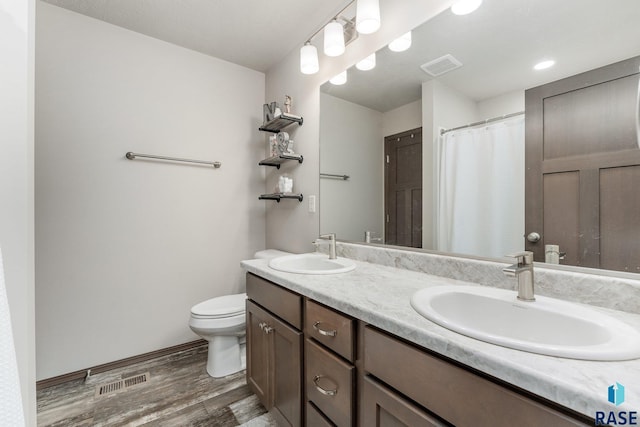 bathroom with toilet, vanity, and hardwood / wood-style flooring