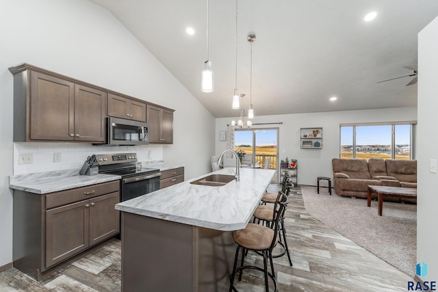 kitchen with a kitchen bar, an island with sink, stainless steel appliances, pendant lighting, and sink