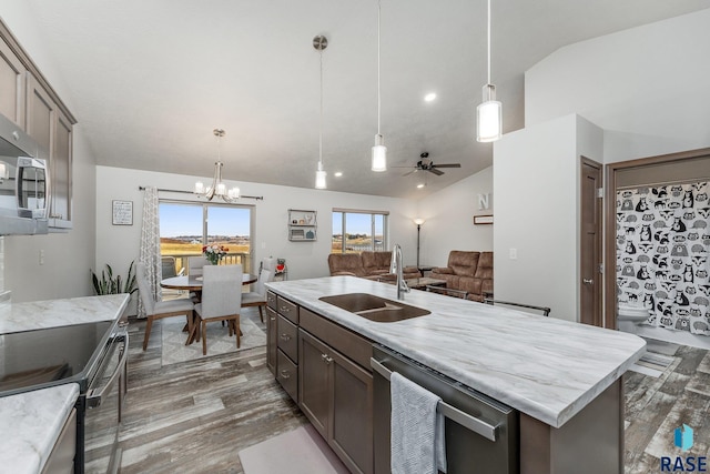 kitchen featuring lofted ceiling, sink, hanging light fixtures, and a center island with sink